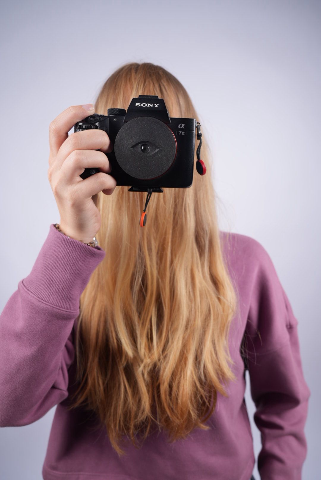 Studentka fotí bezzrcadlovkou Sony Alpha, tvář zakrytá vlasy